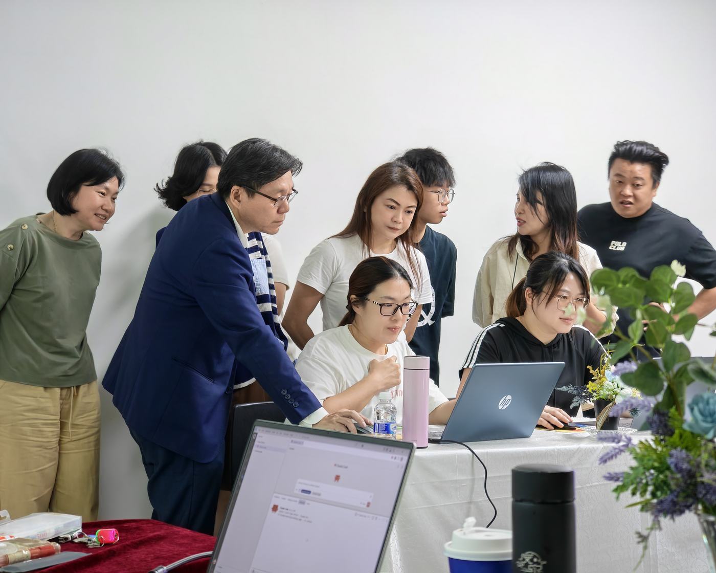 老师弯身和几位学员一起看笔记本电脑屏幕